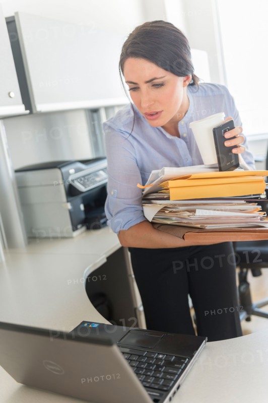 Business woman holding stack of documents and coffee cup.