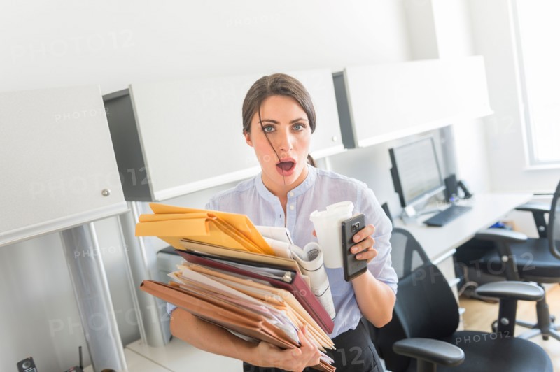 Business woman holding stack of documents in office.