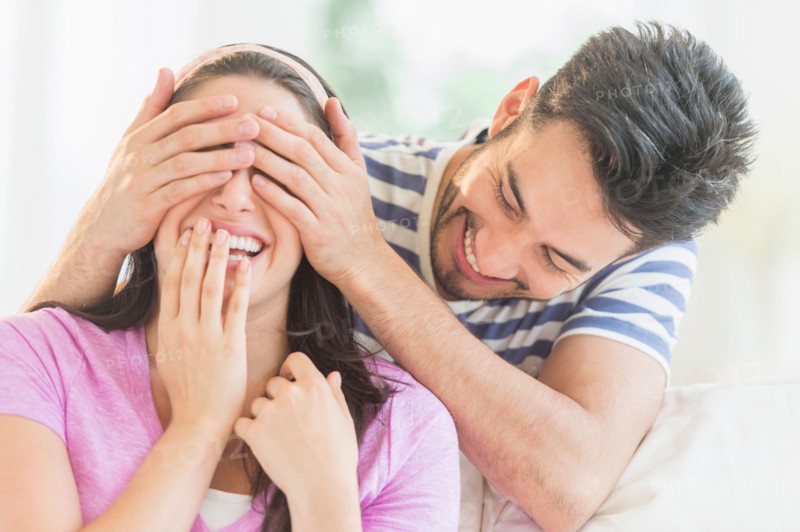 Man covering woman's eyes with his hands.