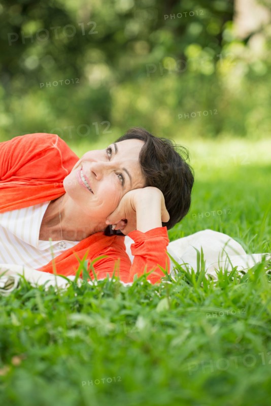 Mature woman lying on grass.