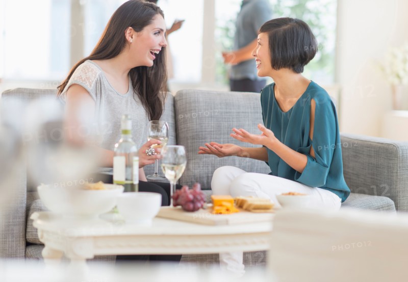 Two friends sitting on sofa and talking.