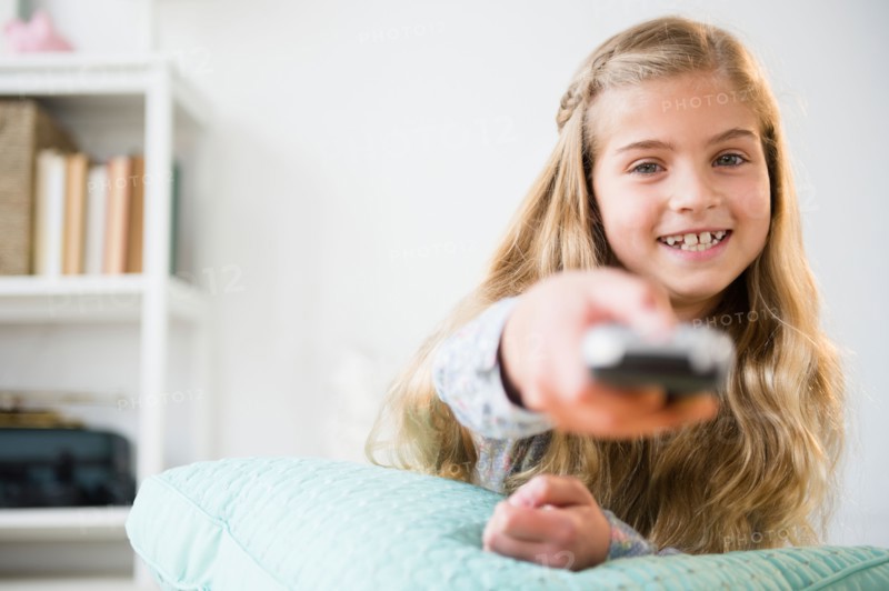 Girl (8-9) holding remote control