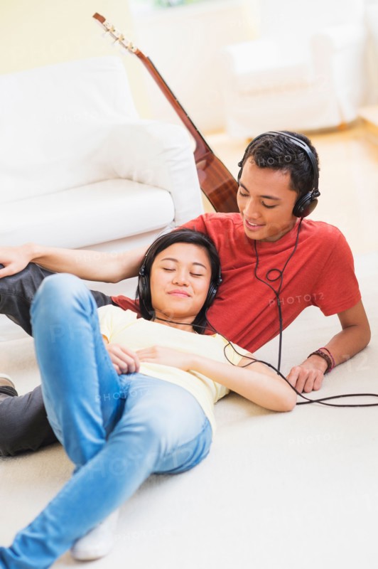 Young woman and man listening music with headphones on