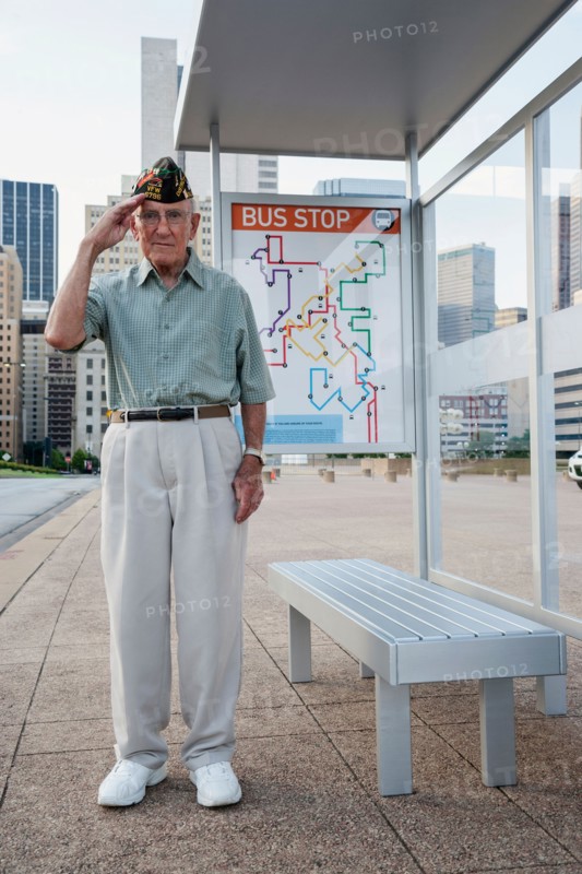 Senior man standing and saluting at bus stop