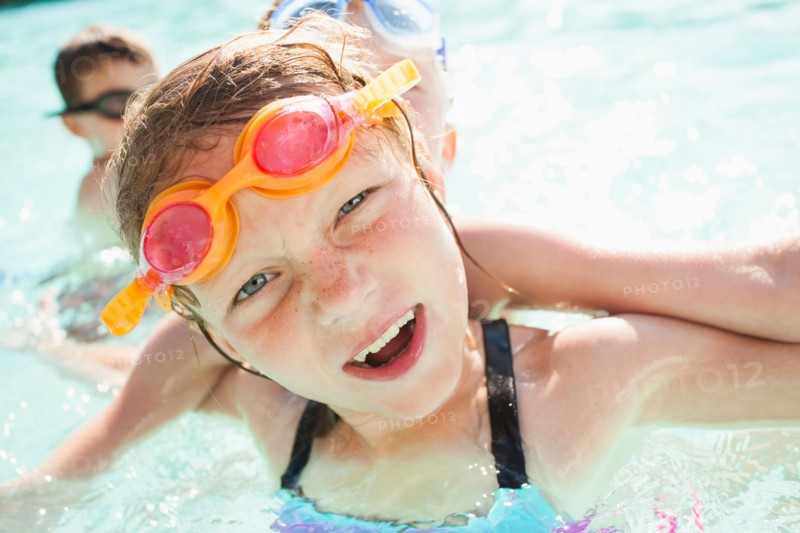 Children (4-5, 8-9) playing in swimming pool