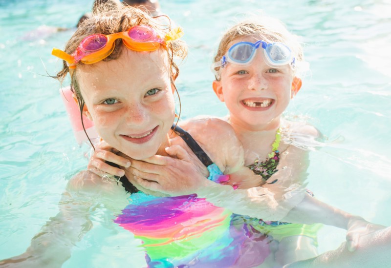 Girlfriends (4-5, 8-9) playing in swimming pool