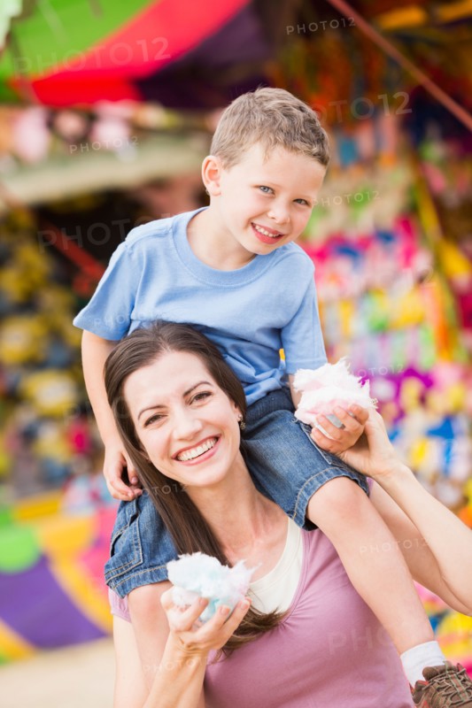 Happy mother with son (4-5) in amusement park eating cotton candy