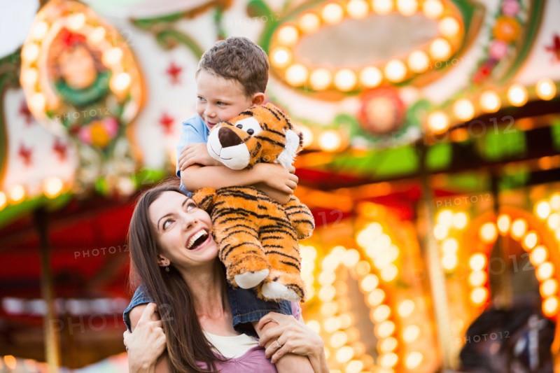 Mother giving her son (4-5) piggyback ride in amusement park