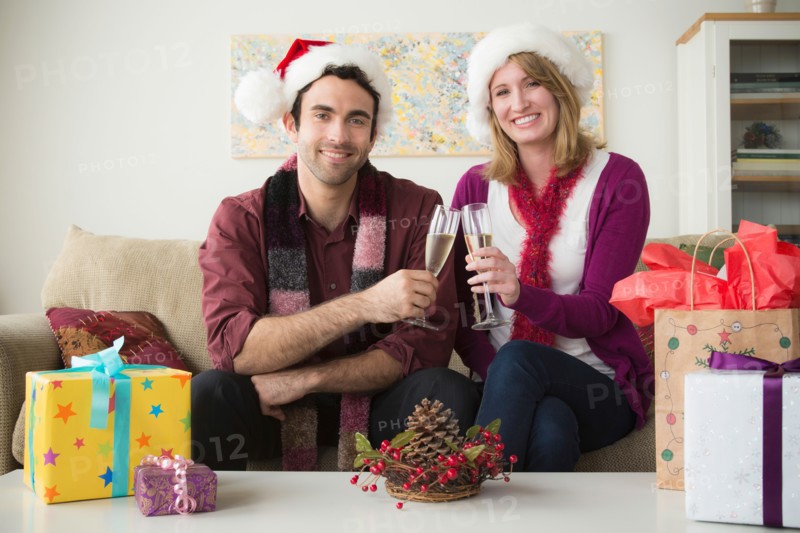 Portrait of young couple wearing santa hats drinking champagne