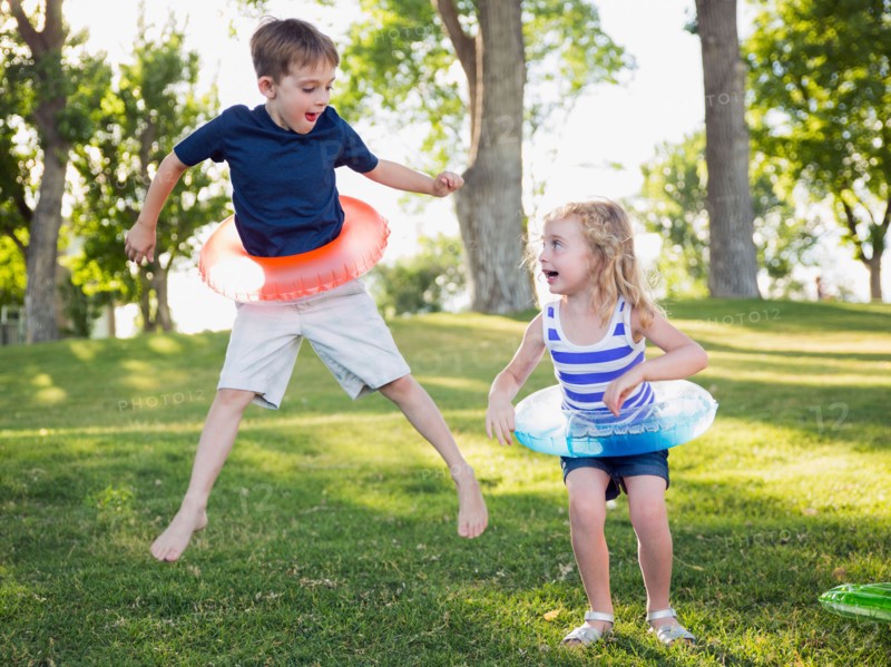 Two kids (4-5, 6-7) playing with inflatable rings in park