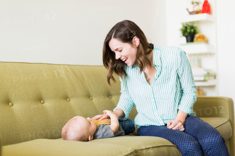 Mother sitting on sofa playing with baby boy (6-11 months)