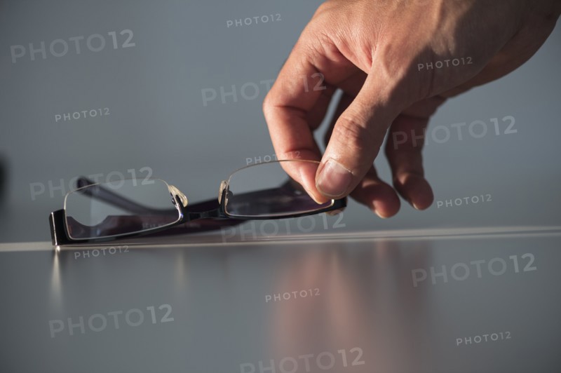 Studio shot of hand reaching for eyeglasses.