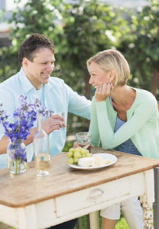 Couple sitting at table outdoors.
