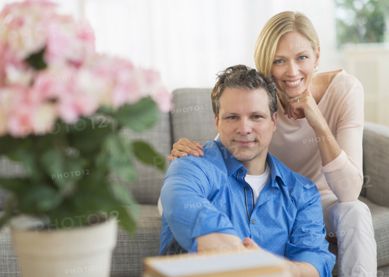 Portrait of couple sitting on sofa.