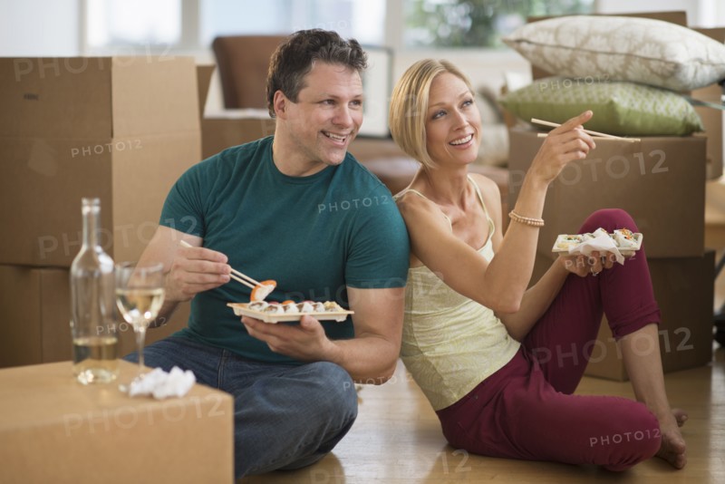 Couple eating sushi in new home.