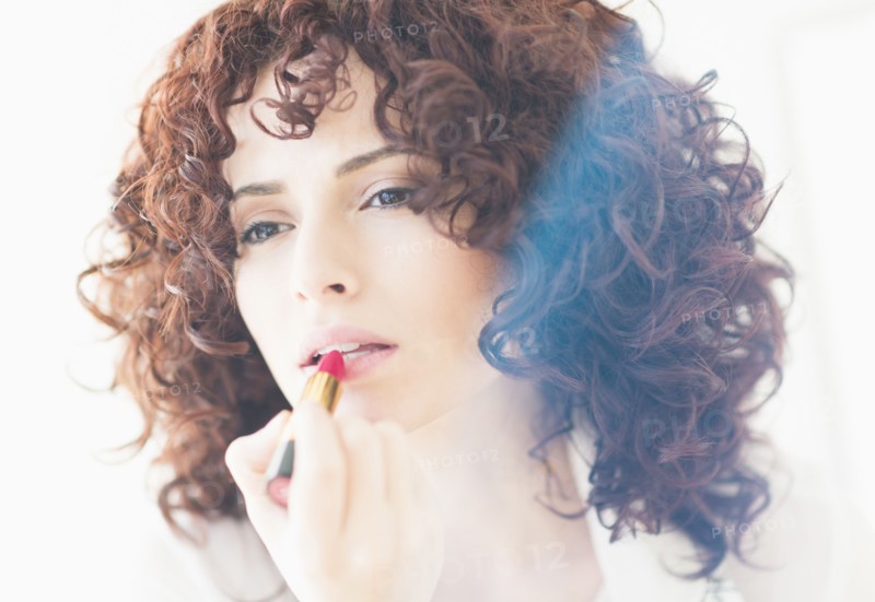 Studio shot of beautiful woman applying lipstick.