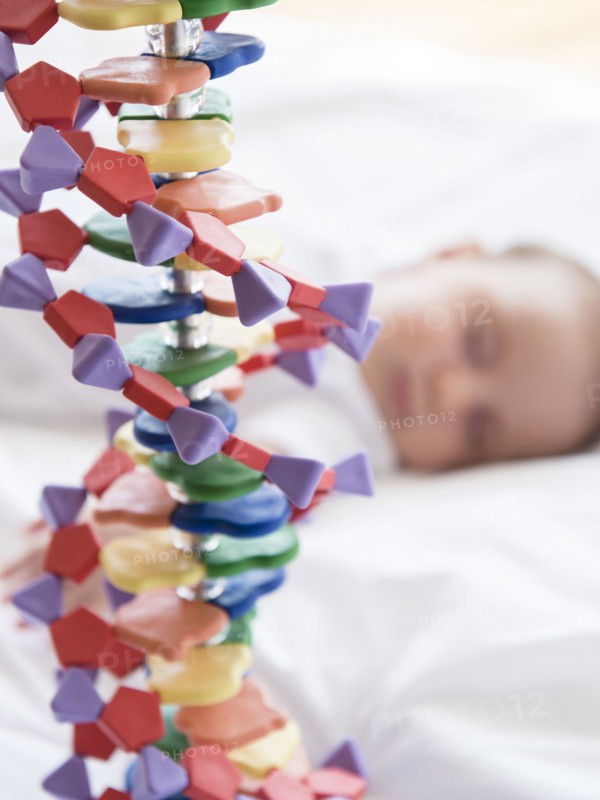 Baby girl (2-5 months) sleeping in bed behind DNA model.
Photo : Jamie Grill
