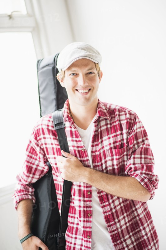Portrait of man carrying guitar bag.
Photo : Daniel Grill