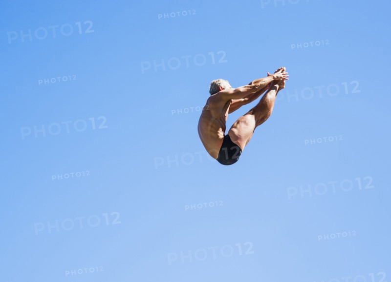 Athletic swimmer mid-air against blue sky.
Photo : Daniel Grill