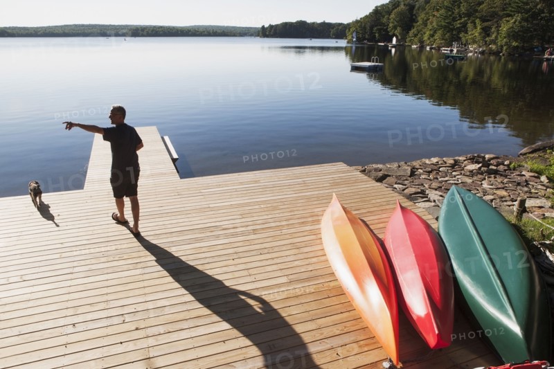 Rear view of man standing on jetty pointing at something. USA, New York State, Wurtsboro.
Photo : fotog