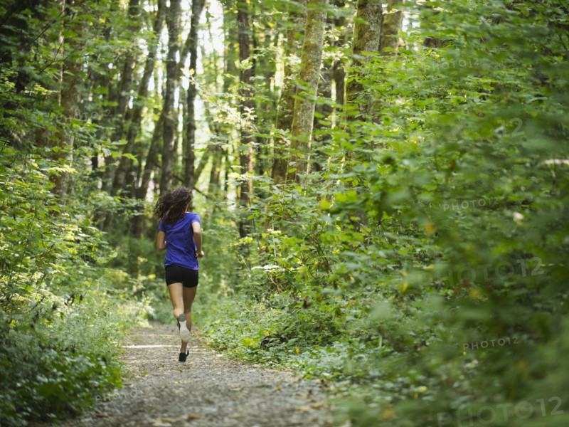 Rear view of young women jogging in forest. USA, Oregon, Portland.