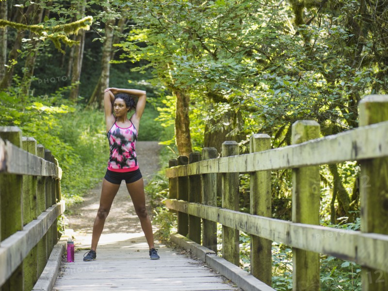 Young women stretching on footbridge. USA, Oregon, Portland.