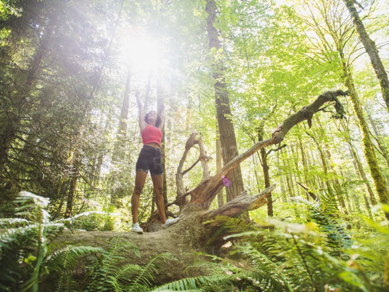 Young woman standing on log in forest. USA, Oregon, Portland.