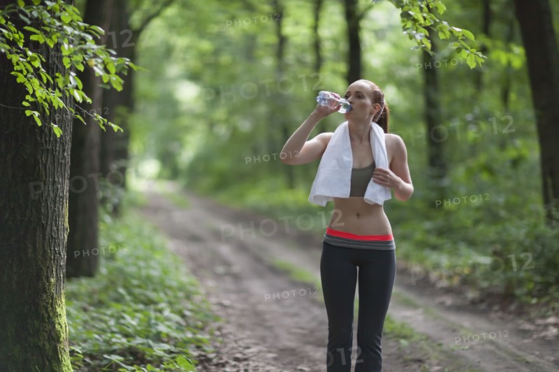 Woman drinking water during jogging in forest. The Netherlands, Erp.
Photo : Mark de Leeuw