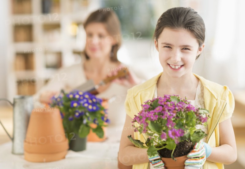 Girl (8-9) and mother potting flowers.