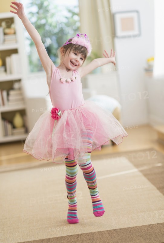 Girl (4-5) wearing tutu dancing in living room.