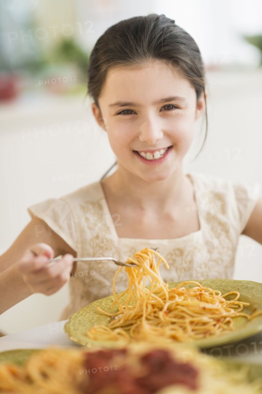 Portrait of girl (8-9) eating pasta.