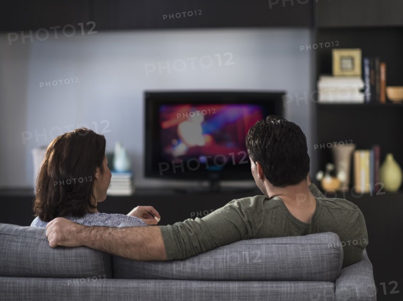 Rear view of couple watching tv.