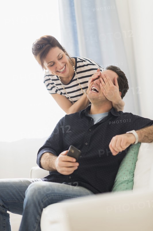 Woman covering man's eyes.