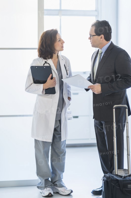 Pharmaceutical representative talking to female doctor.