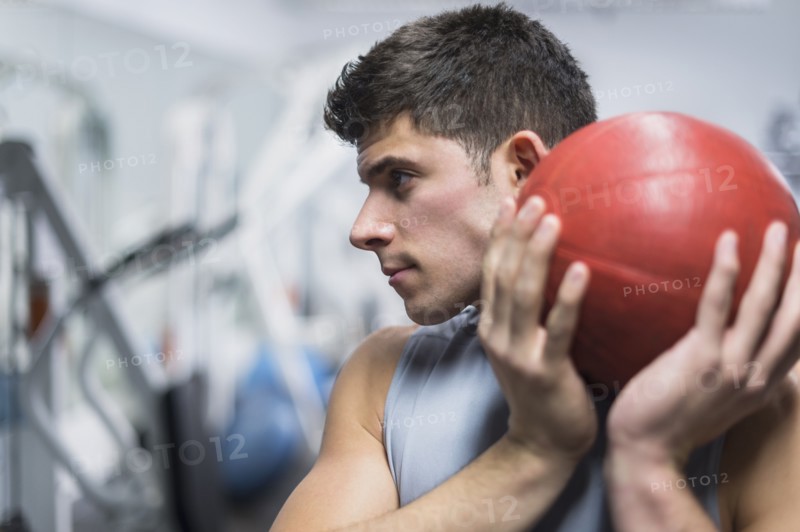 Young man at gym holding medicine ball.