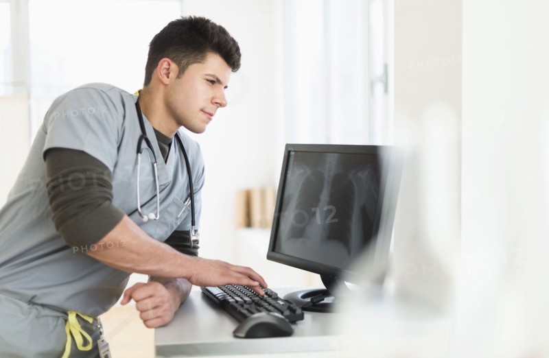 Young man with stethoscope working at computer.