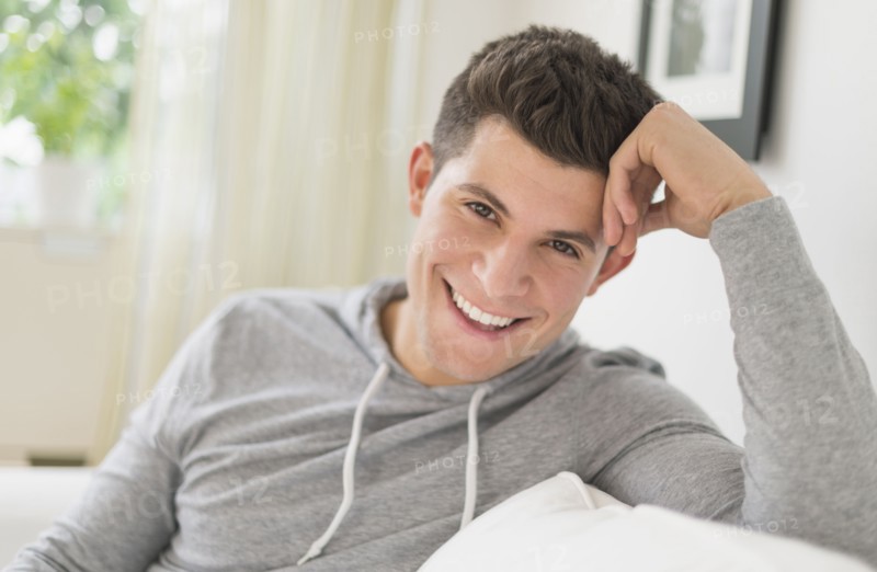 Young man sitting on sofa and smiling.