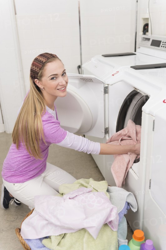 Woman loading laundry into washing machine.