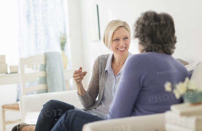 Two women sitting on coach talking.