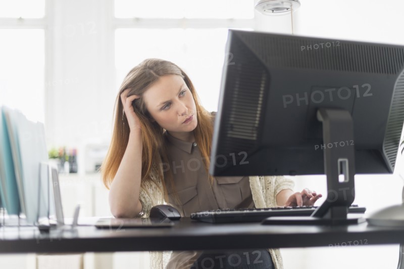Portrait of young woman working on computer in office.