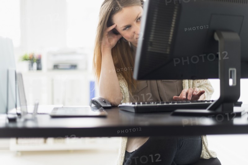 Portrait of young woman working on computer in office.