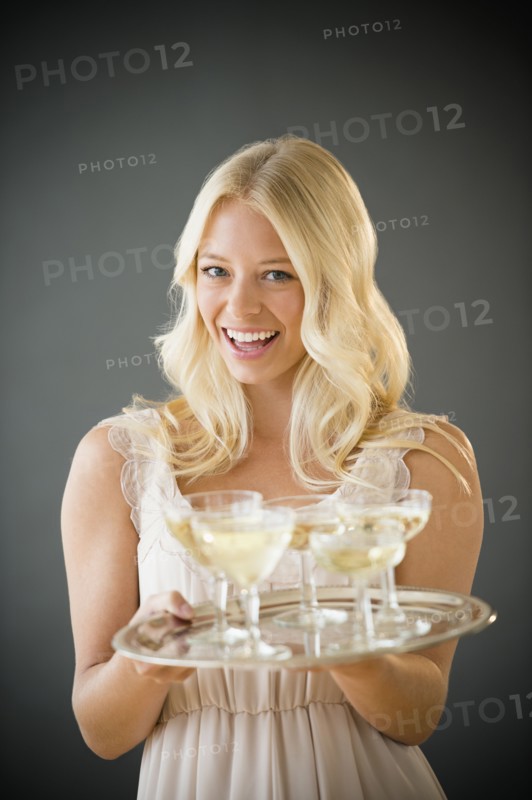 Portrait of young woman holding tray with champagne.
Photo : Jamie Grill