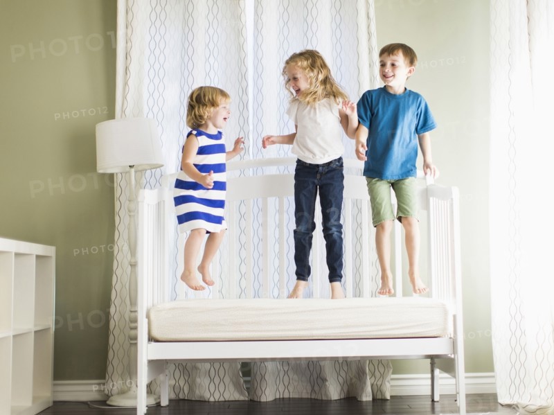 Girls (4-5, 6-7) and boy (8-9) jumping on sofa.
Photo : Jessica Peterson