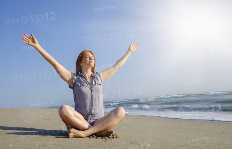 Woman practicing yoga on beach.