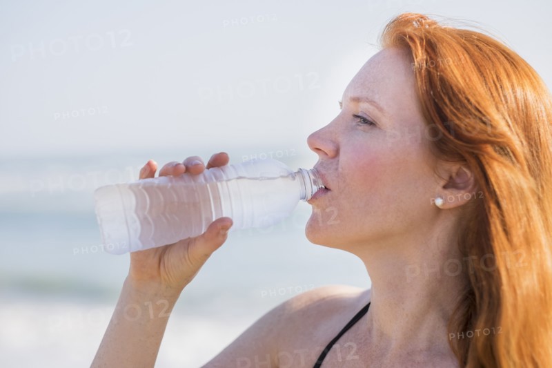 View of woman drinking water on beach.