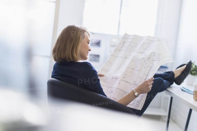 Business woman looking at blueprint in office.