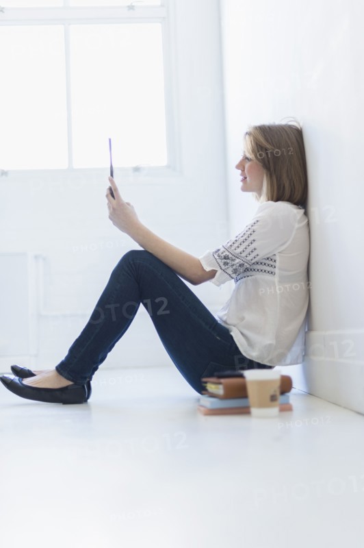 Young woman sitting on floor and using digital tablet.
