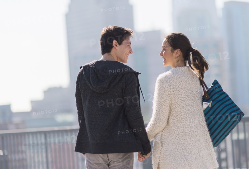 Young couple walking, buildings in background.