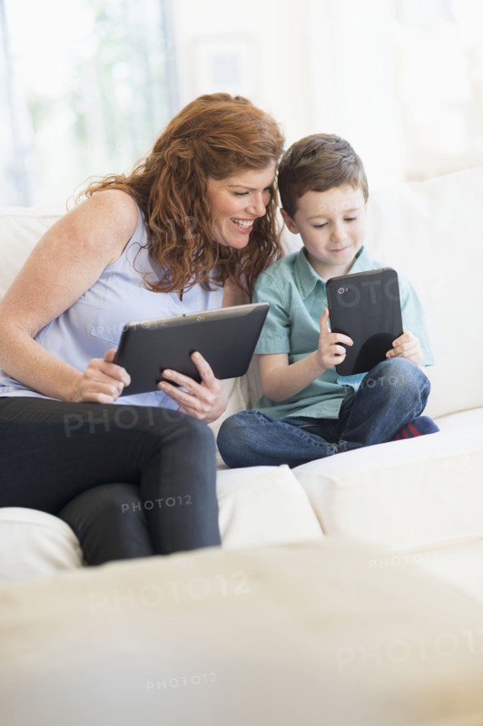 Mother and son (6-7) using digital tablets.