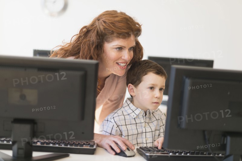 boy (6-7) and teacher using computer.